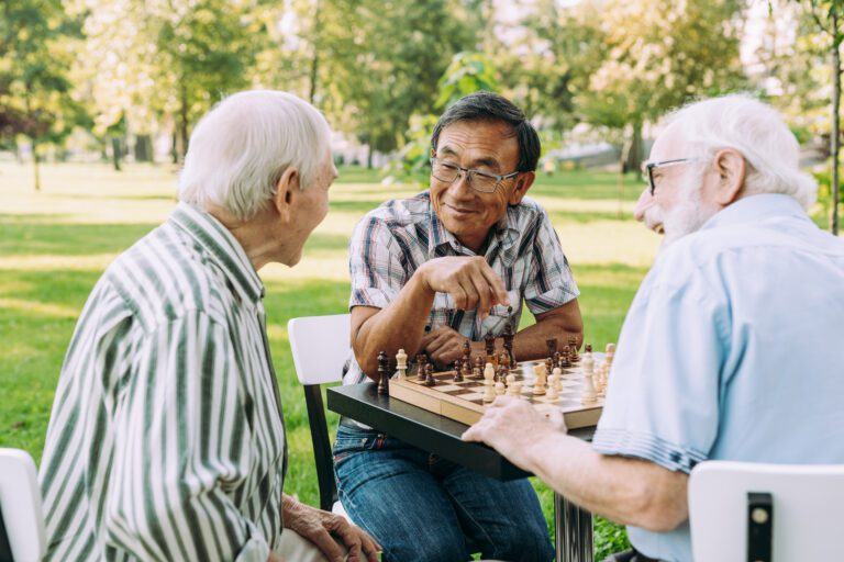 Group of senior friends playing chess game at the park.