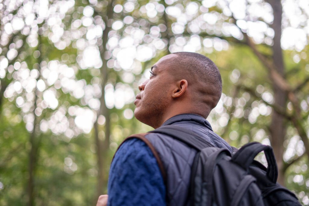 Man looking at trees in forest during nature walk in autumn