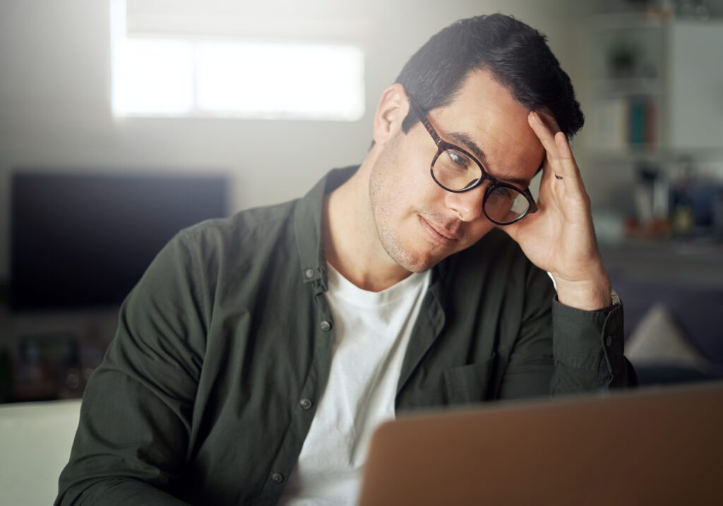 Man holding head with his hand looking at laptop