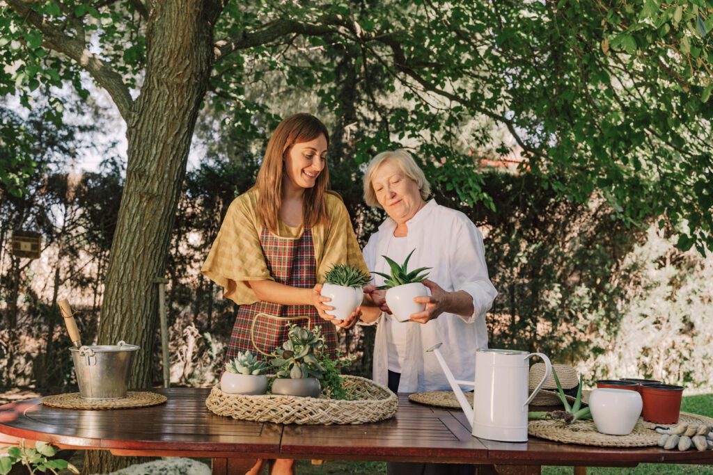 Mother and daughter holding potted plants while standing at table in yard