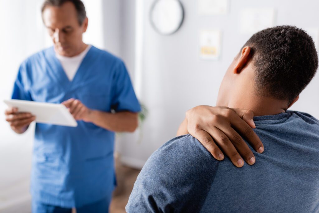 Injured man at doctor's appointment with referring provider for recent neck pain personal injury