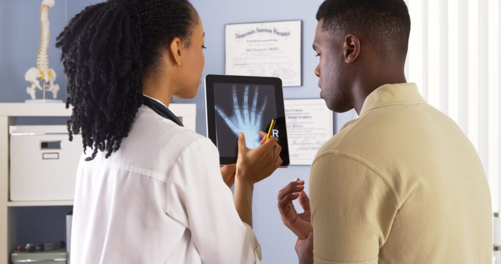 Doctor explaining x-ray of hand to patient suffering from personal injury