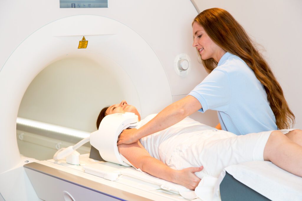 MRI technologist preparing patient for a scan of the shoulder with magnetic resonance tomography MRI